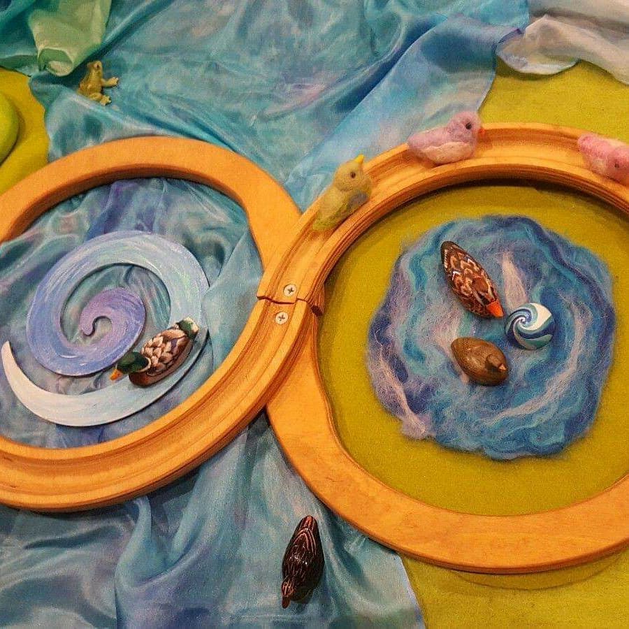 Hand-painted play silks arranged with wooden rings and miniature figures